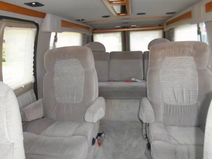 Comfortable RV rental interior showing grey plush seats & windows. Ideal for travel.. Ford Econoline 150 2004