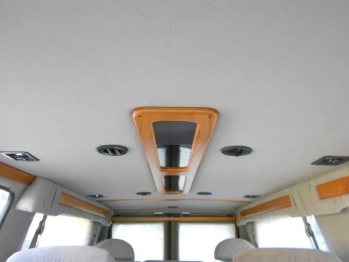 Plush RV rental interior: overhead console, vents, lights, and wood trim create a cozy space.. Ford Econoline 150 2004