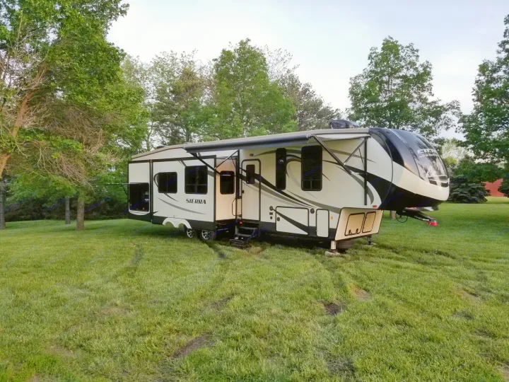 Spacious Sierra fifth-wheel RV rental parked on a green lawn with trees in the background, ideal for camping and travel.. Forest River Sierra 2018