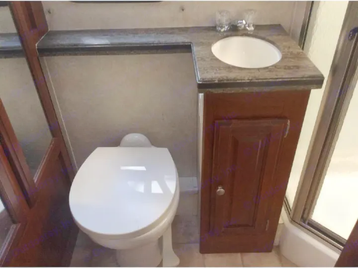 RV rental bathroom: A compact space featuring a white toilet, dark countertop sink vanity, and shower enclosure.. Phoenix USA Cruiser 2552 2011