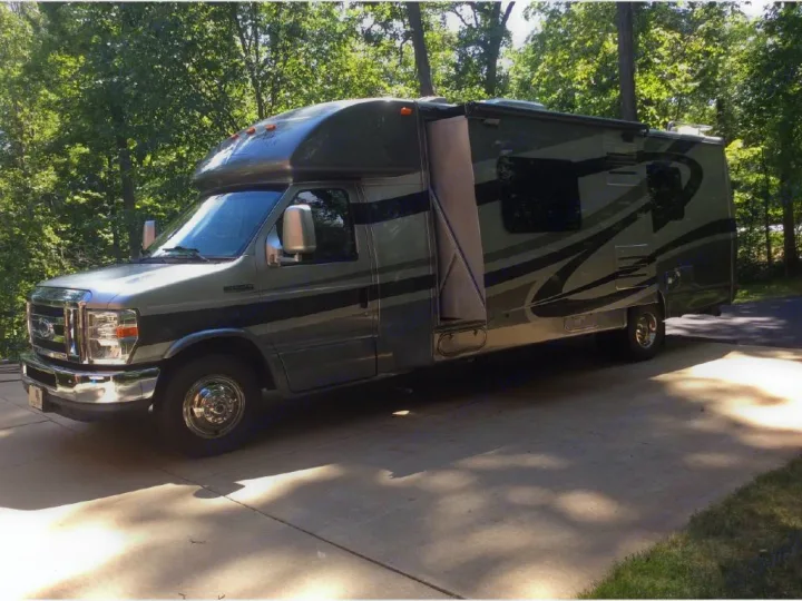 Gray RV rental: a Class C motorhome with an extended slide-out section, parked on a sunny driveway.. Phoenix USA Cruiser 2552 2011