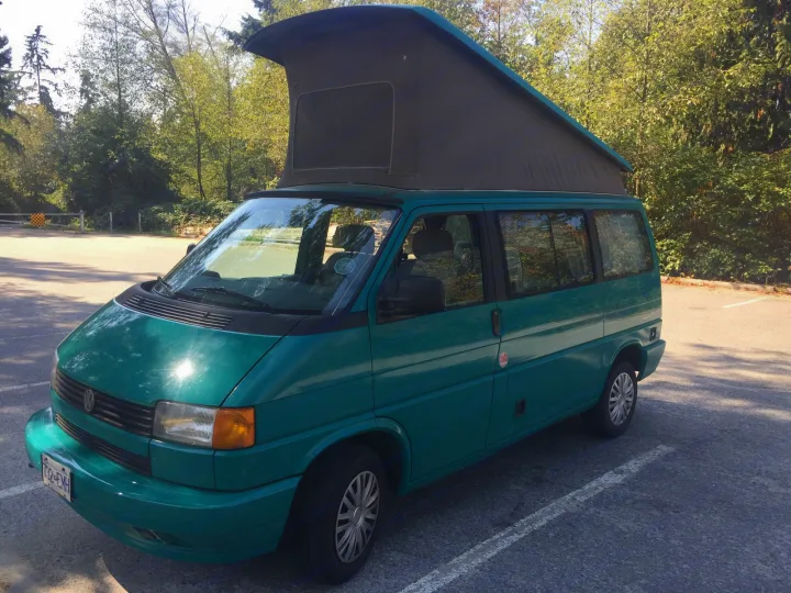 Teal VW pop-top camper van, a versatile RV rental parked in nature. Ideal for travel and adventure seekers.. Volkswagen Westfalia 1992