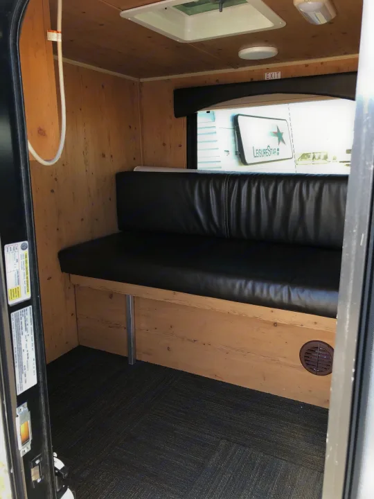 Step inside this RV rental! Features a black upholstered bench, warm wood paneling, and an overhead vent.. Sunset Park & Rv Inc. Other 2017
