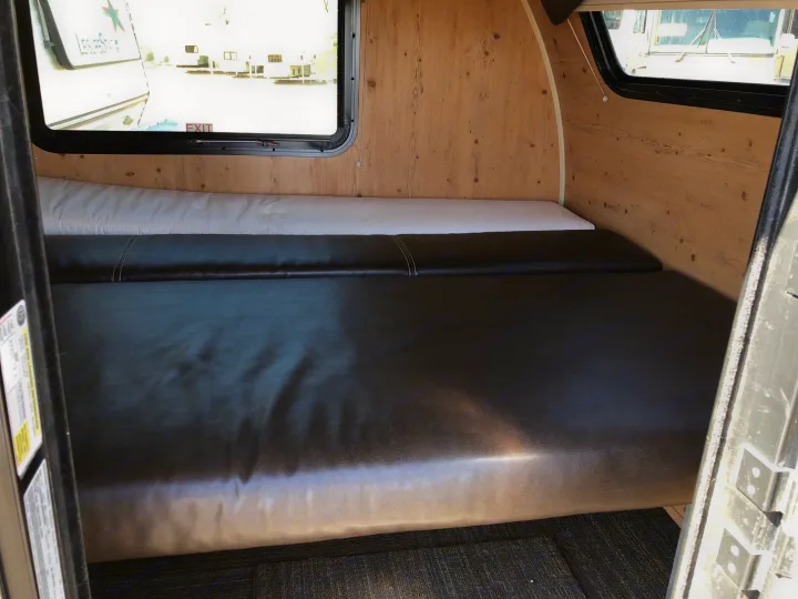Cozy RV rental interior with a comfortable bed, dark cushions, and light wood paneling, ready for travel.. Sunset Park & Rv Inc. Other 2017