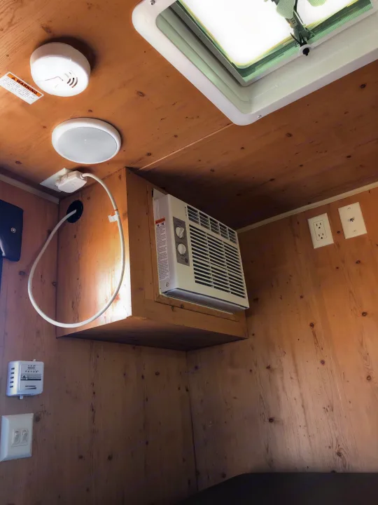 View inside an RV rental showing wood paneled walls, ceiling, AC unit, smoke detector, and electrical fixtures.. Sunset Park & Rv Inc. Other 2017