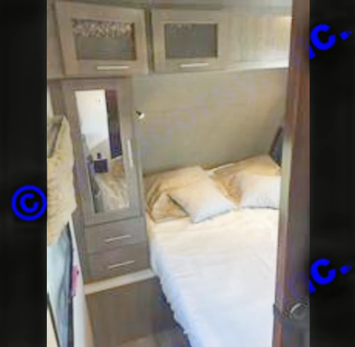 This RV rental offers a compact bedroom with a comfortable bed, overhead cabinets, and a mirror. Ideal for travel.. Forest River Surveyor 2019