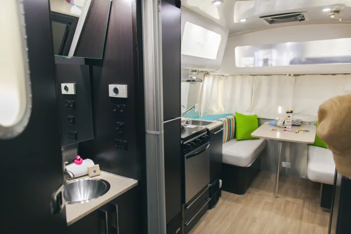 Well-equipped RV rental interior with a compact kitchen, dining area, and bathroom vanity, ideal for travel.. Airstream 19 Bambi International 2012