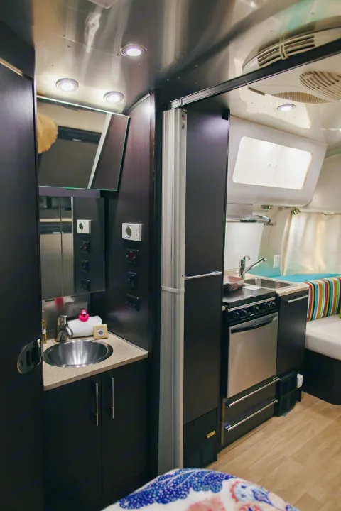 This RV rental's sleek interior showcases a compact kitchen with a sink/stove, a bathroom vanity, and cushioned seating.. Airstream 19 Bambi International 2012