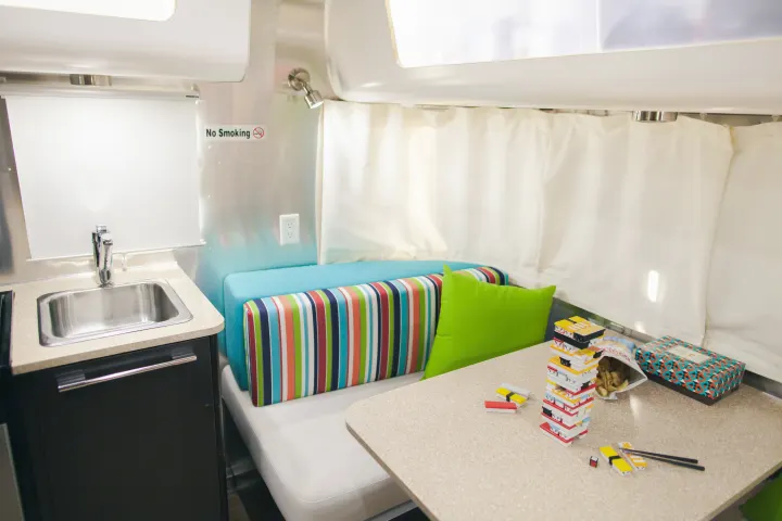 Compact RV rental living space featuring a kitchen, bright seating, and a table with a sushi Jenga game.. Airstream 19 Bambi International 2012