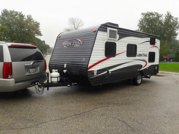 Silver SUV towing an Aspen Trail travel trailer, an excellent RV rental option for camping adventures.. Keystone ASPEN TRAIL 1700 2016