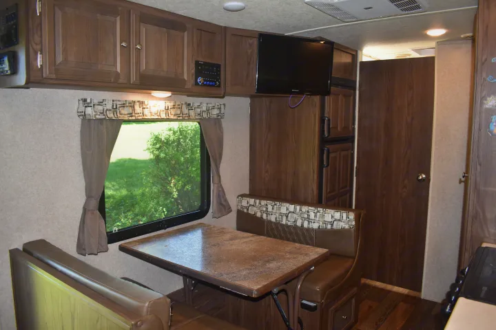 Cozy RV rental interior with a dinette, overhead cabinets, and built-in refrigerator. Ideal living space for campers.. Forest River Rockwood Mini Lite 2017