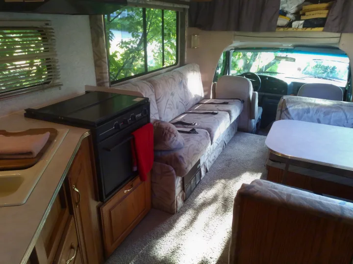 Bright RV rental interior: Full kitchen, sofa, dinette, & cab. Sunlight highlights the cozy, functional living space.. Jayco Eagle 1996