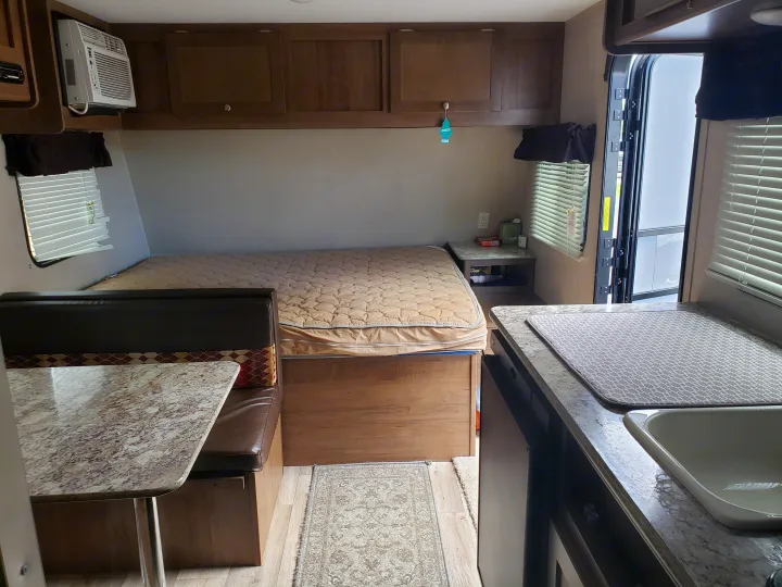 Cozy RV rental interior featuring a compact kitchen, dinette, and bed area, perfect for travel adventures.. Keystone ASPEN TRAIL 1700 2016