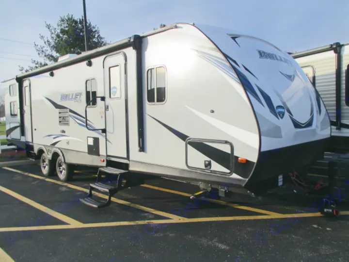 Modern grey Bullet travel trailer, ideal for an rv rental, parked on asphalt with yellow lines. Features awning, steps.. Keystone Bullet 2019