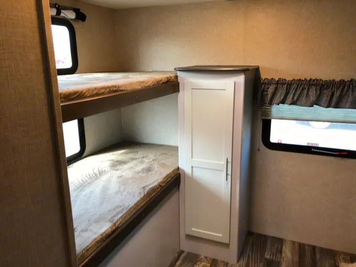 RV rental interior: cozy bunk beds with soft mattresses, storage cabinet, and window with blinds.. Keystone Bullet 2019