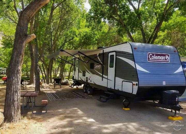 Coleman travel trailer rv rental in a lush, shaded campsite with awning extended. Perfect for outdoor camping.. Coleman Lantern 2018