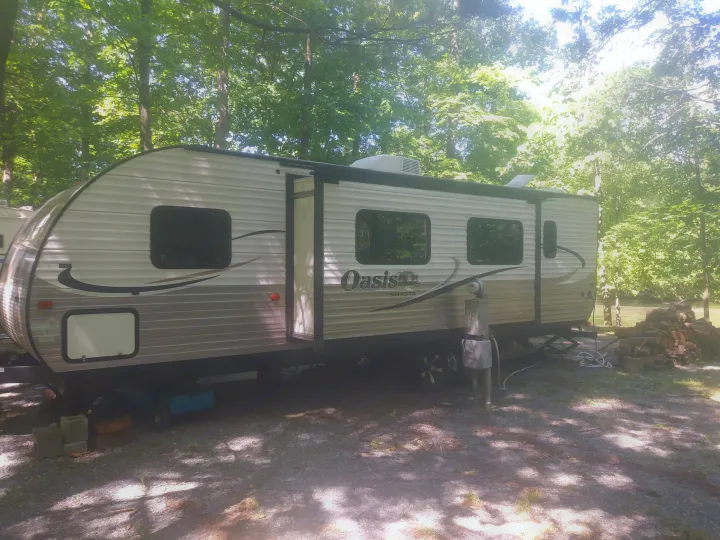 Experience nature with this spacious Oasis by Shasta RV rental parked at a tranquil, tree-lined campsite by the water.. Shasta Oasis 2013