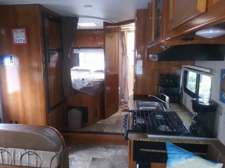 Interior is spacious and well appointed. Interior rear view of bed area and kitchen.. Coachmen Leprechaun 2018