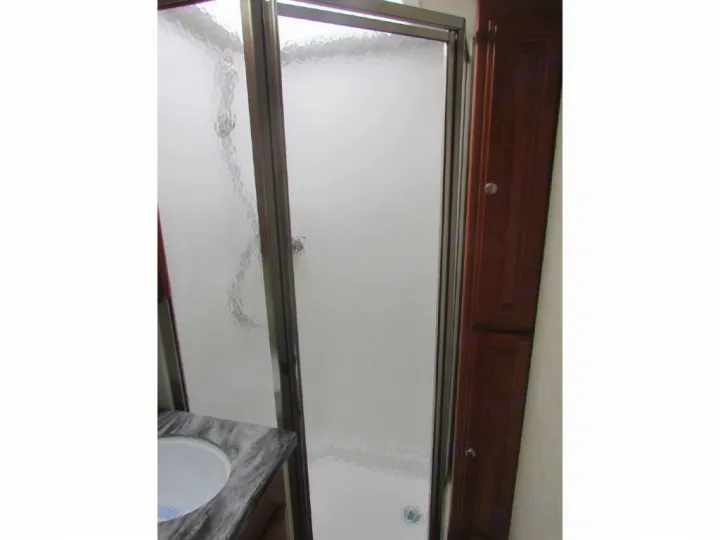 RV rental bathroom with frosted glass shower, marble sink, and wood cabinetry.. Phoenix USA Cruiser 2552 2011