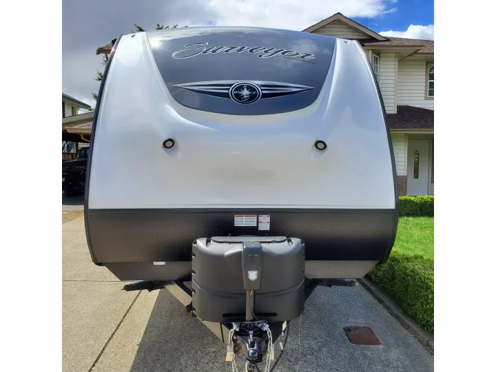 Front exterior of a white and black Surveyor travel trailer, showing its logo & propane tanks. Perfect for rv rental.. Forest River Surveyor 2019