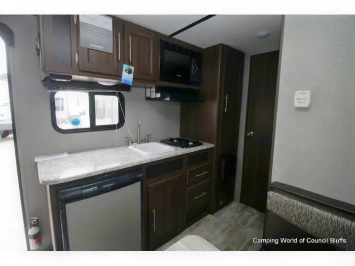 RV rental kitchen: sink, stovetop, microwave, fridge, dark wood cabinets & counter.. Crossroads Zinger 2020