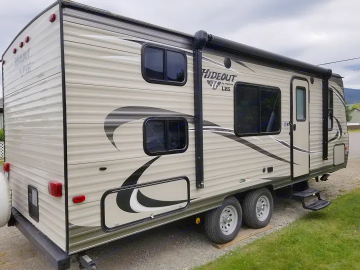 Side view of a Keystone Hideout travel trailer, a spacious RV rental, with an extended awning.. Keystone Hideout 2017