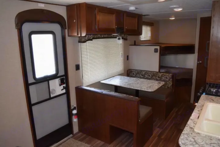 RV rental interior featuring a wooden dinette, kitchen, bunk beds, and main entry door with screen.. Keystone Hideout 2017