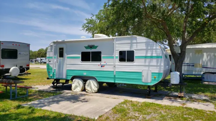A Retro travel trailer RV, white and teal, parked in a sunny RV park, ideal for an RV rental.. Riverside Rv 189R Retro 2018