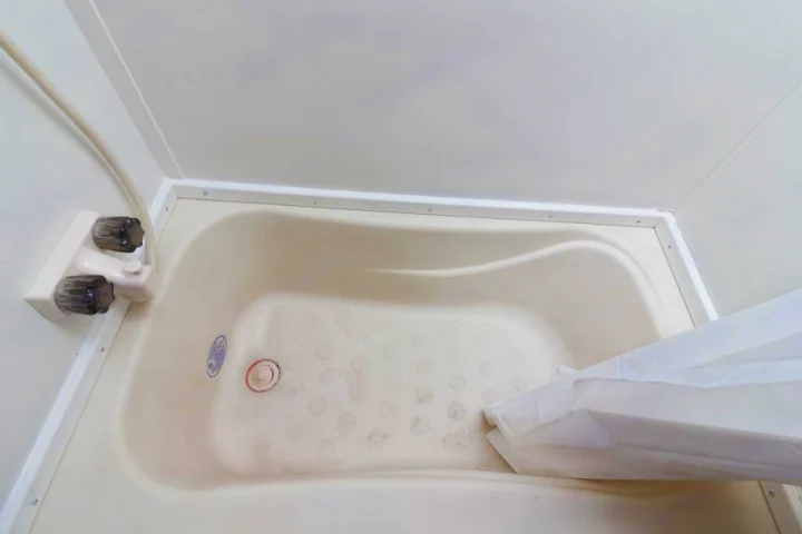 Clean, compact off-white bathtub with non-slip bottom and shower in an RV rental unit.. Gulf Stream Kingsport 2019