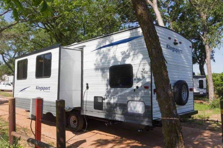 Kingsport RV rental travel trailer with an extended slide-out at a shaded campsite, ready for your outdoor adventure.. Gulf Stream Kingsport 2019