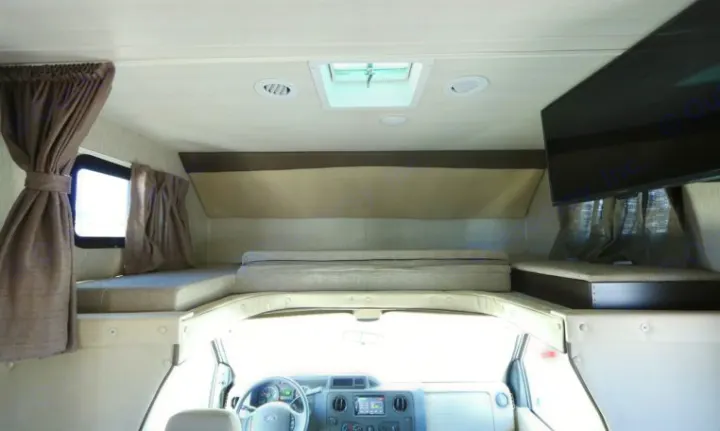 Inside this RV rental: the driver's cockpit, an overhead cab-over bed, and a side sleeping area with a mounted TV.. Nexus RV Phantom 2019
