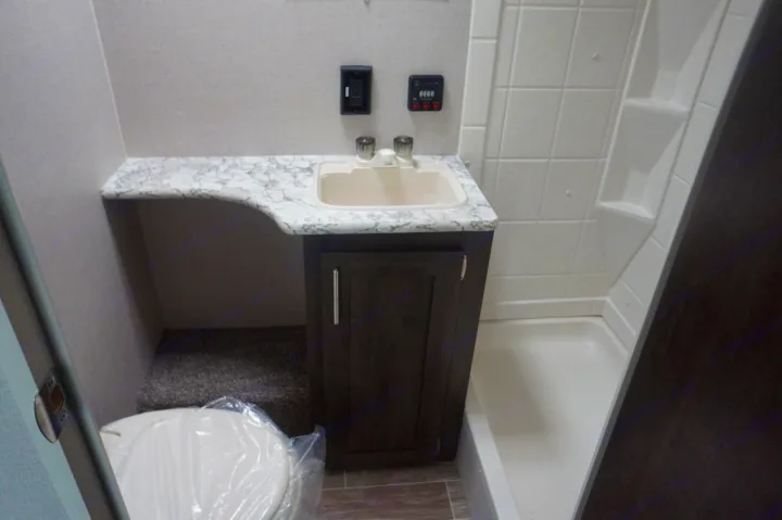 Compact RV rental bathroom: vanity with sink, shower stall, and a covered toilet.. K-Z Manufacturing sportsmen 301 2020