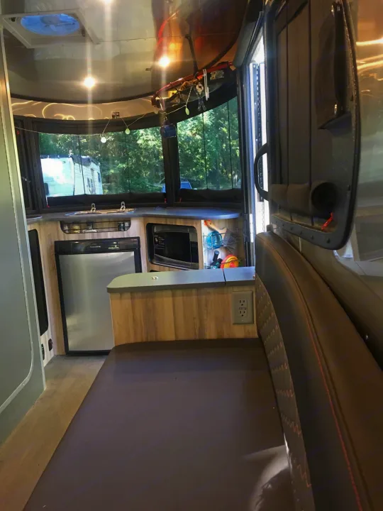Cozy rv rental interior: modern kitchen with Dometic fridge, microwave, and comfortable dinette. Ready for your adventure!. Airstream Base Camp 2017