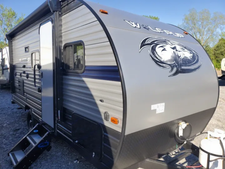 Grey Wolf Pup travel trailer RV rental, featuring steps, windows, and a distinctive wolf logo on the front.. Forest River Cherokee Wolf Pup 2019