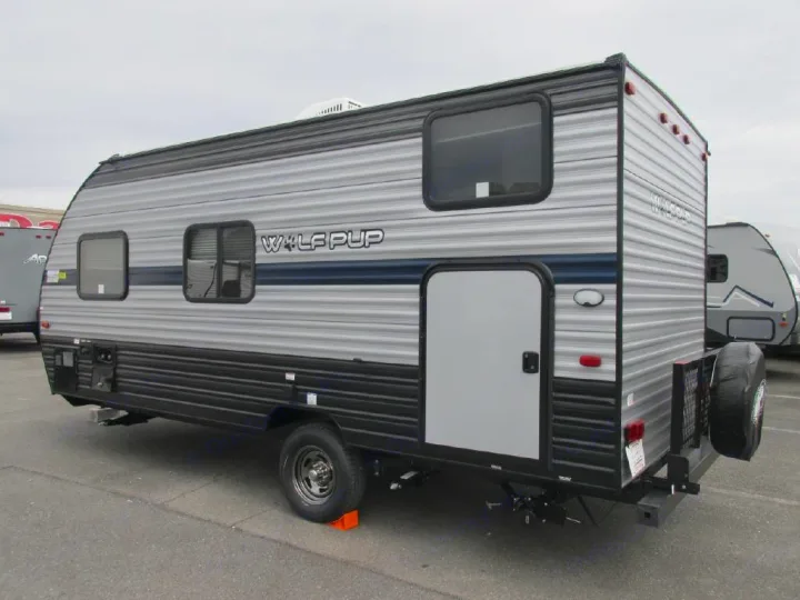 Side and rear view of a parked Wolf Pup travel trailer, a silver and black RV ideal for an rv rental.. Forest River Cherokee Wolf Pup 2019