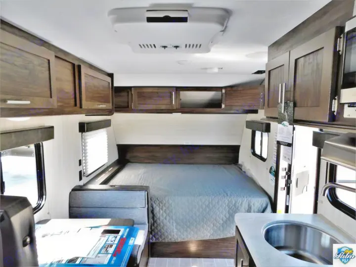 Inside this RV rental, a compact yet functional interior features a cozy bed, kitchen sink, and ample overhead storage for travel.. Forest River Cherokee Wolf Pup 2019