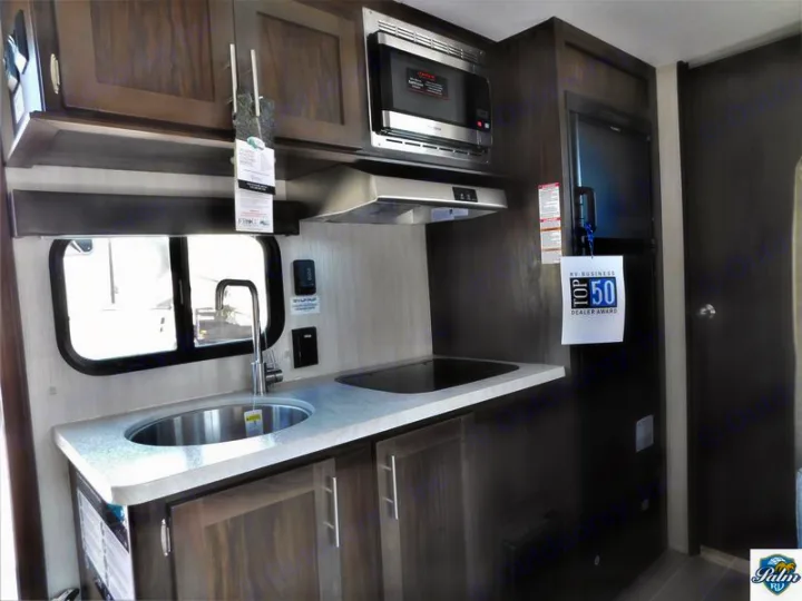 Compact RV rental kitchen with stainless steel sink, stovetop, microwave, and refrigerator.. Forest River Cherokee Wolf Pup 2019