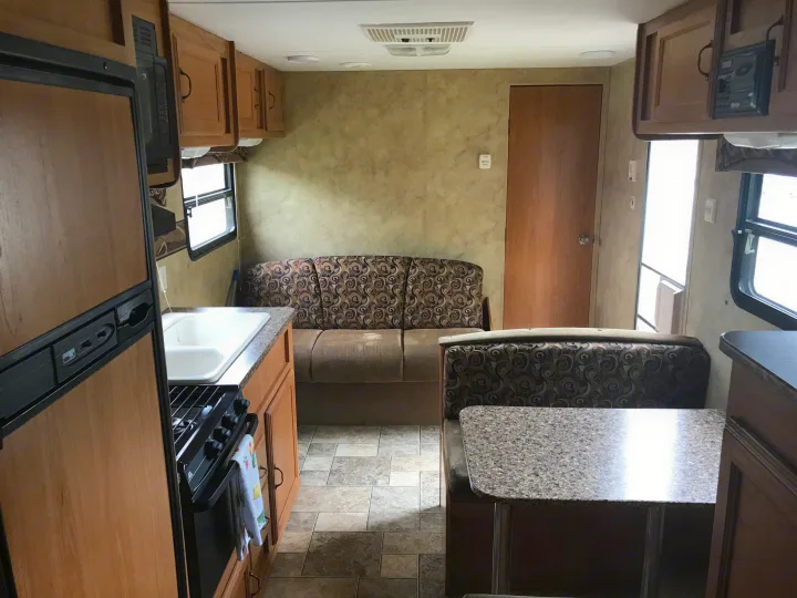 Explore this RV rental's interior: well-equipped kitchen with fridge/stove, comfy sofa, and dinette. Perfect for trips!. Keystone Hideout 2009