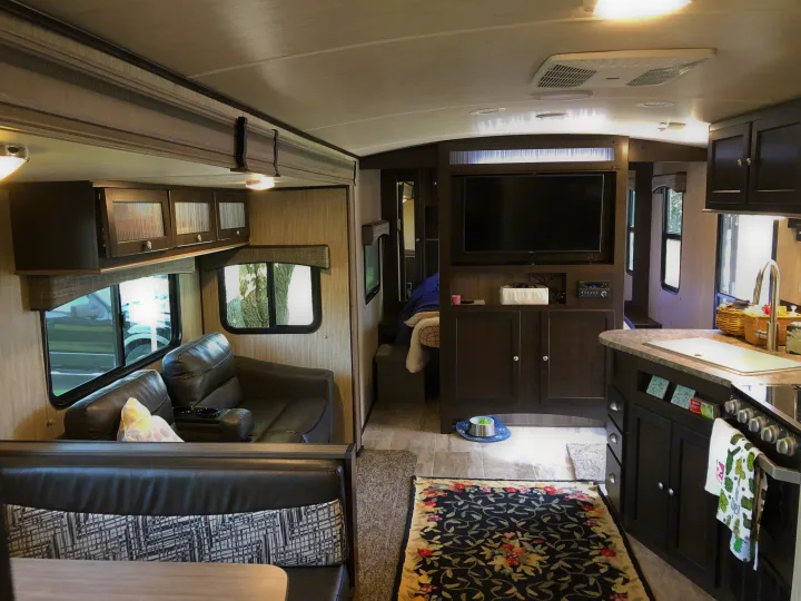 Cozy RV rental interior showing a modern kitchen, living area with recliners, and glimpse of the bedroom.. Heartland Sundance 2019