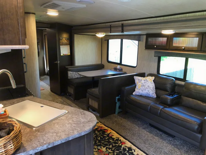 Explore this modern RV rental: a well-appointed kitchen, dining booth, and comfortable living area with sofa.. Heartland Sundance 2019