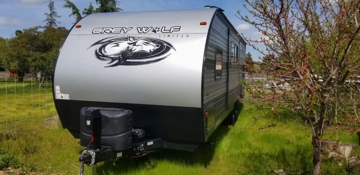 Grey Wolf travel trailer, a great RV rental for your outdoor adventures, set on lush green grass.. Forest River Cherokee Grey Wolf 2019