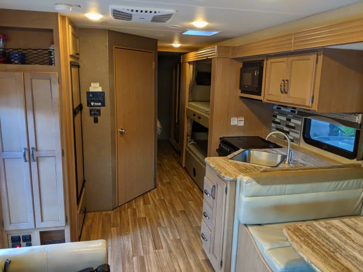 Experience travel convenience! This RV rental showcases a well-equipped interior with a kitchen, dining area, and bunk beds.. Thor Motor Coach A.C.E 2019