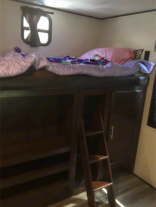 Cozy RV rental bunk bed with ladder and storage. Features a comfy top bunk and compact interior window.. Jayco Other 2020