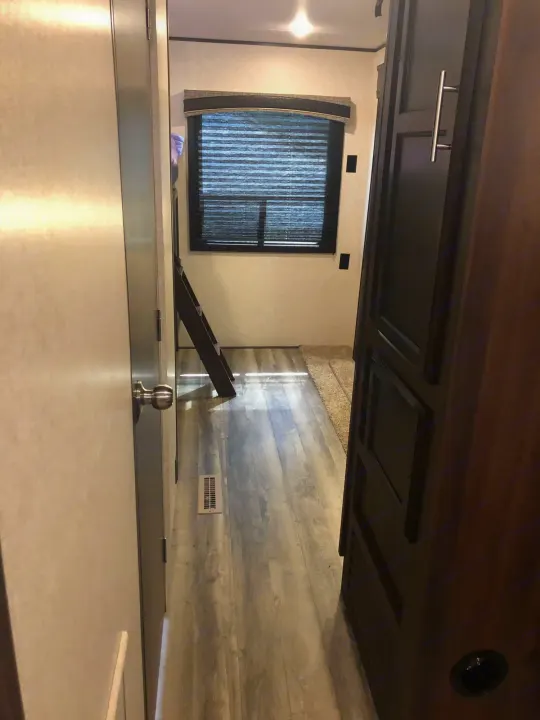 Explore this modern RV rental interior: a bright hallway leads to a bedroom with a window, ladder, and wood floors.. Jayco Other 2020