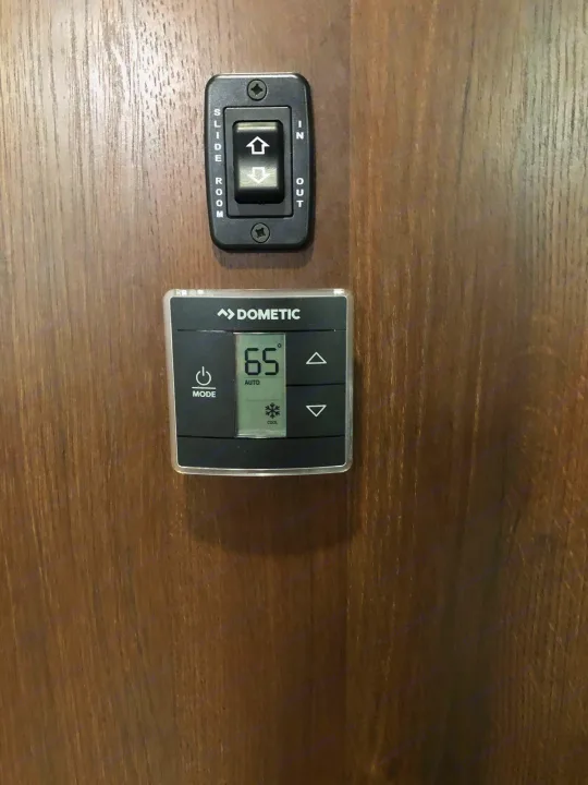 RV rental interior controls: a slide-out switch and Dometic thermostat set to 65° cool. Essential for comfort.. Jayco Other 2020