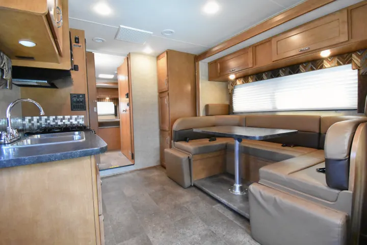 RV rental interior showcasing a well-equipped kitchen area with a sink and stovetop, and a comfortable dining booth.. Winnebago Minnie Winnie 2018