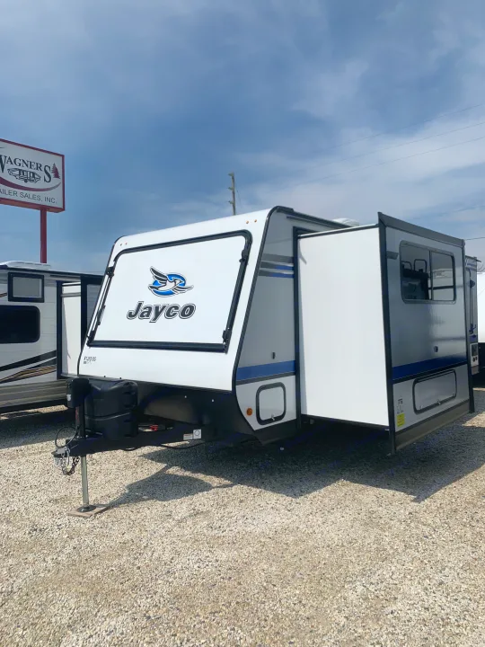 A Jayco travel trailer with an extended slide-out at a dealership, ready for RV rental or purchase.. Jayco Jay Feather 2019