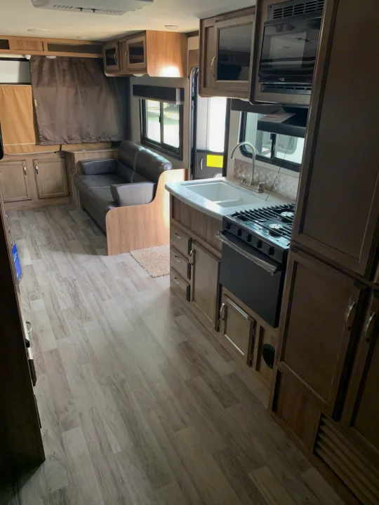 Spacious RV rental interior featuring a full kitchen with stove, sink, microwave, and a comfortable living area with sofa.. Jayco Jay Feather 2019