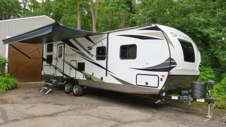 White Solaire travel trailer with extended awning, ideal for RV rental adventures.. Palomino Solaire Ultra Lite 268BHSK 2020