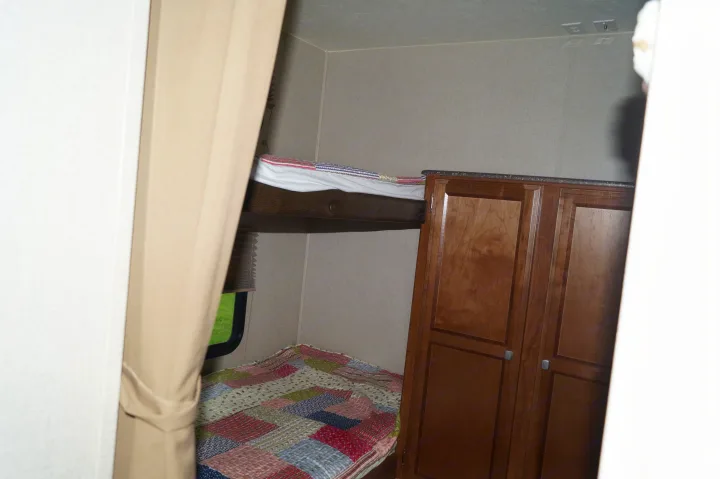 RV rental: Interior shows a cozy sleeping area with upper/lower bunk beds, a storage cabinet, and a window for comfortable travel.. Coachmen Freedom Express 2017